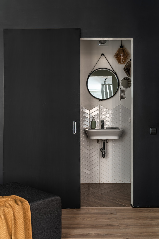 Immagine di un bagno di servizio nordico di medie dimensioni con pareti nere, pavimento in laminato, pavimento beige, piastrelle bianche, piastrelle a listelli e lavabo sospeso
