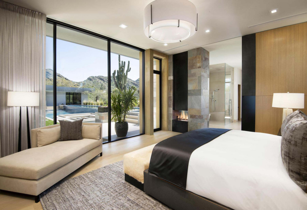 This is an example of an expansive contemporary master bedroom in Phoenix with white walls, medium hardwood floors, a two-sided fireplace and a metal fireplace surround.