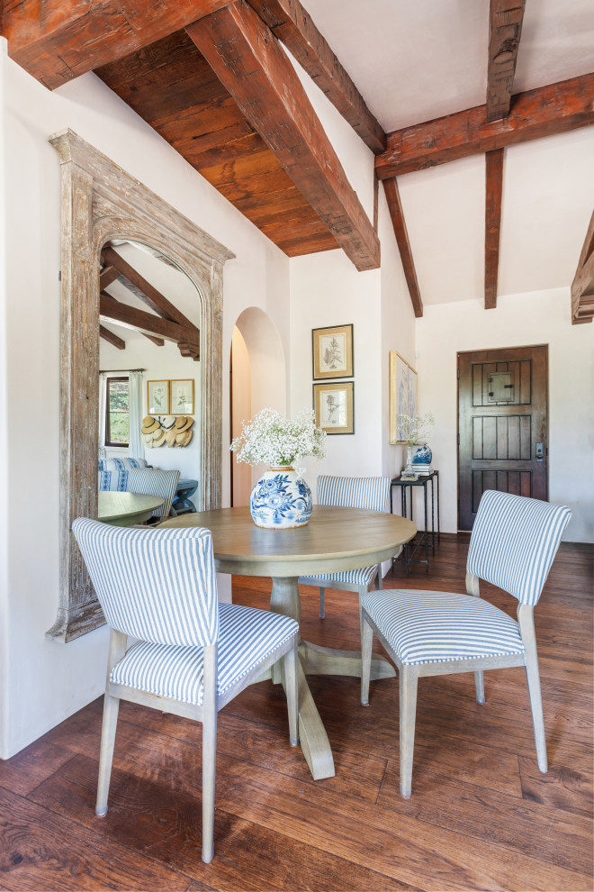 This is an example of a small mediterranean dining room in Santa Barbara with beige walls, medium hardwood floors and exposed beam.