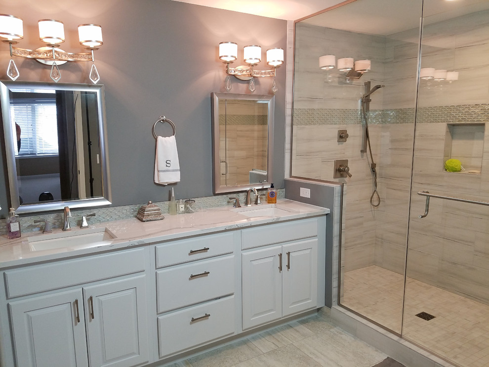 This is an example of a mid-sized transitional master bathroom in Other with raised-panel cabinets, white cabinets, an alcove shower, a two-piece toilet, gray tile, porcelain tile, grey walls, porcelain floors, an undermount sink and engineered quartz benchtops.