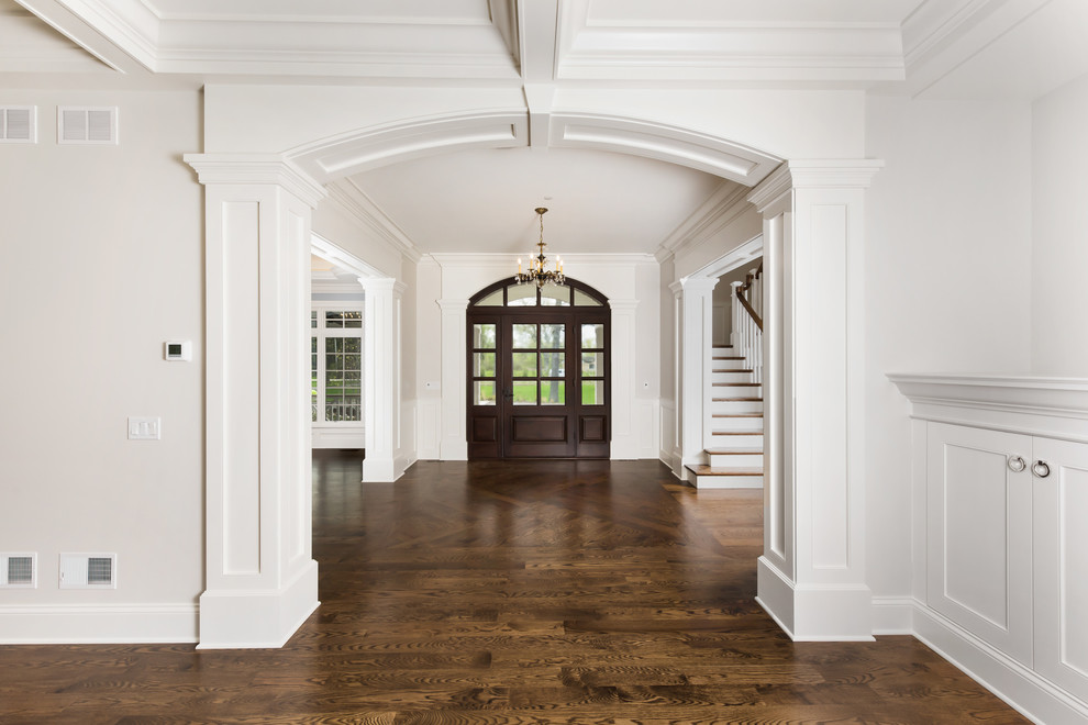 This is an example of a large transitional front door in Chicago with white walls, dark hardwood floors, a single front door, a dark wood front door and brown floor.
