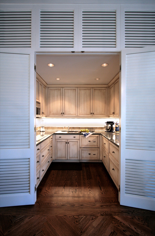 This is an example of a tropical u-shaped separate kitchen in Charleston with distressed cabinets.