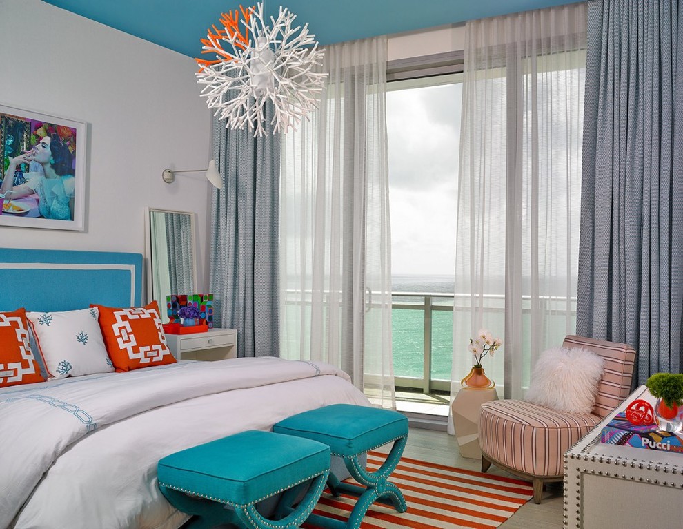 Inspiration for a mid-sized beach style master bedroom in Miami with white walls, light hardwood floors, no fireplace and grey floor.