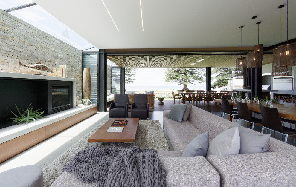 Inspiration for a mid-sized contemporary open concept living room in Central Coast with grey walls, concrete floors, a standard fireplace, a concrete fireplace surround, a built-in media wall and grey floor.