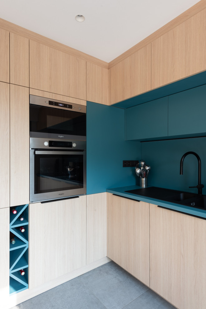 Inspiration for a small scandinavian l-shaped open plan kitchen in Lyon with a single-bowl sink, beaded inset cabinets, light wood cabinets, laminate benchtops, blue splashback, panelled appliances, ceramic floors, no island, grey floor and blue benchtop.