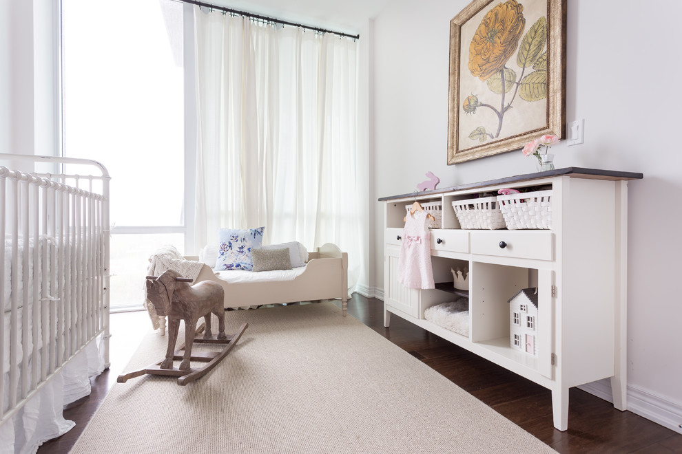 This is an example of a large transitional nursery for girls in Toronto with white walls, dark hardwood floors and brown floor.