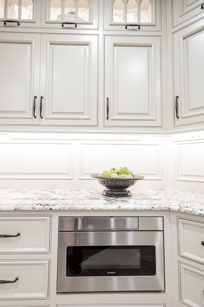 Example of a large transitional porcelain tile and beige floor kitchen design with a farmhouse sink, beaded inset cabinets, gray cabinets, granite countertops, porcelain backsplash, stainless steel appliances, an island and beige countertops
