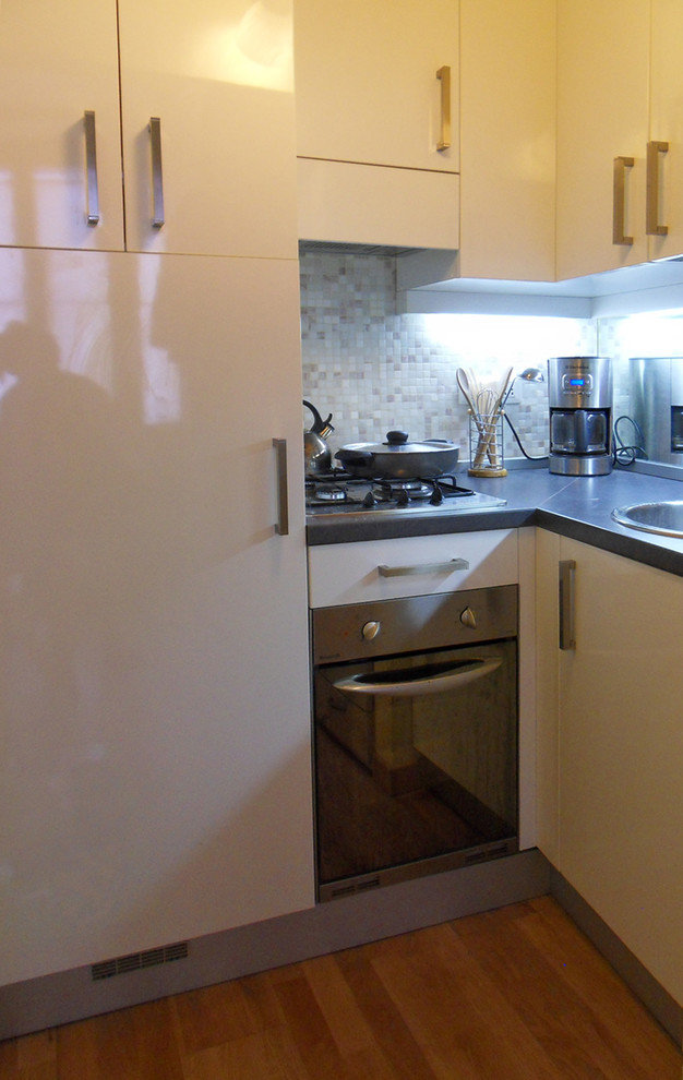Foto di una piccola cucina a L moderna con lavello da incasso, ante lisce, ante bianche, top in laminato, paraspruzzi con piastrelle a mosaico e elettrodomestici in acciaio inossidabile
