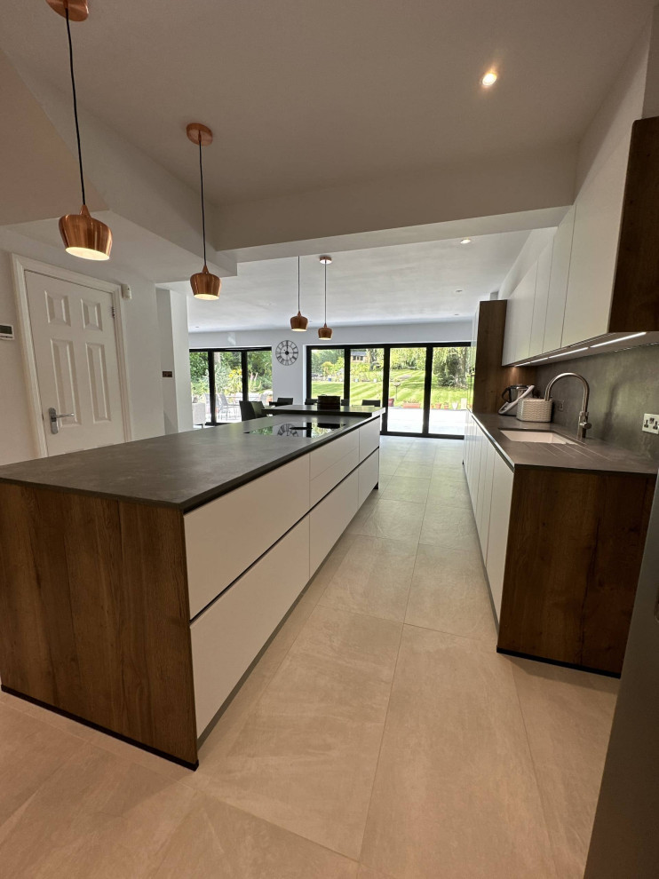 Design ideas for a large scandi l-shaped open plan kitchen in Hertfordshire with an integrated sink, flat-panel cabinets, white cabinets, quartz worktops, black appliances, an island, grey floors, grey worktops, exposed beams and feature lighting.