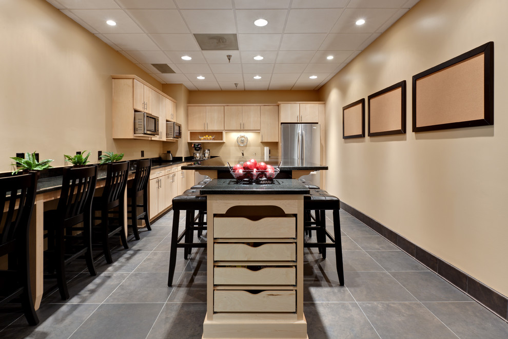 This is an example of a large contemporary l-shaped eat-in kitchen in Atlanta with flat-panel cabinets, light wood cabinets, an undermount sink, granite benchtops, black splashback, stainless steel appliances, porcelain floors, with island, grey floor, granite splashback and black benchtop.