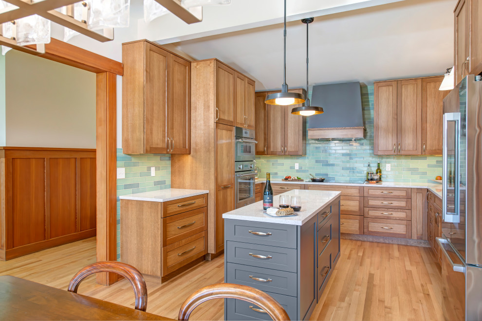 Mid-sized transitional u-shaped medium tone wood floor, brown floor and vaulted ceiling eat-in kitchen photo in Seattle with a double-bowl sink, recessed-panel cabinets, light wood cabinets, quartz countertops, blue backsplash, ceramic backsplash, stainless steel appliances, an island and white countertops