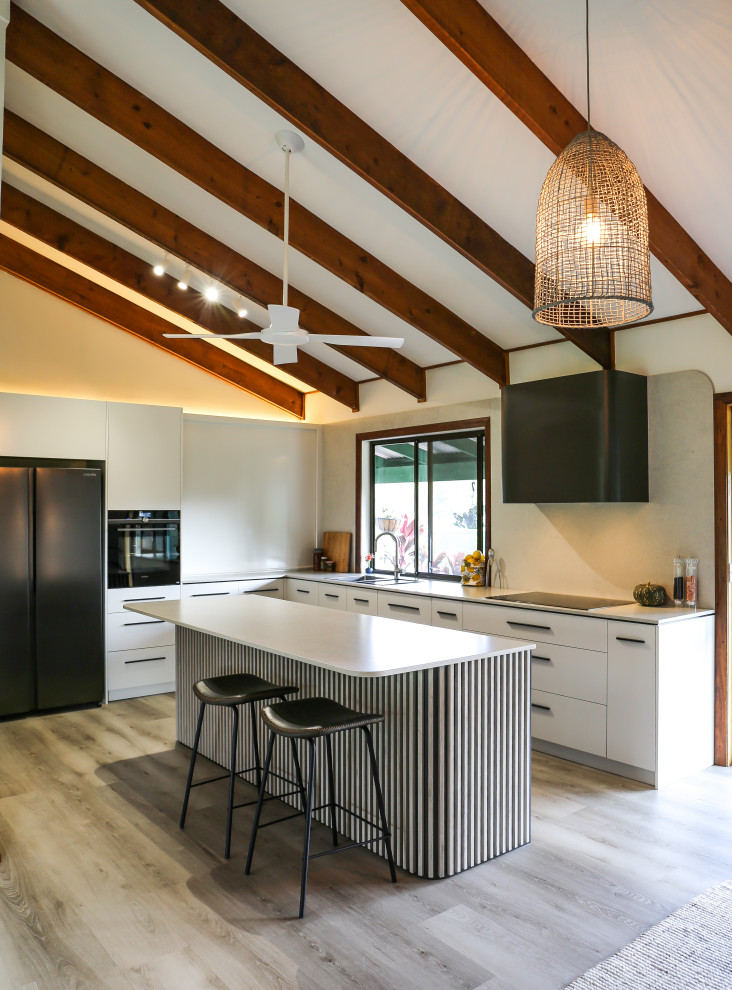 Design ideas for a large contemporary l-shaped eat-in kitchen with a double-bowl sink, flat-panel cabinets, white cabinets, quartz benchtops, multi-coloured splashback, engineered quartz splashback, black appliances, laminate floors, with island, brown floor, multi-coloured benchtop and exposed beam.