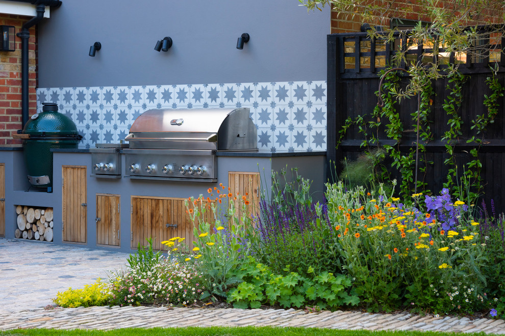 Design ideas for a contemporary back garden for summer in London with natural stone paving and a wood fence.
