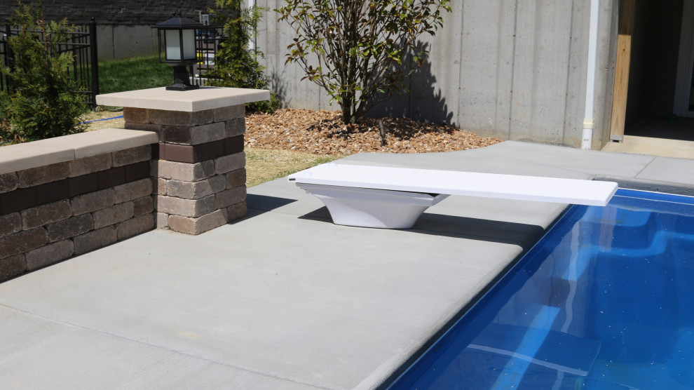 Ispirazione per una grande piscina naturale design rettangolare dietro casa con lastre di cemento