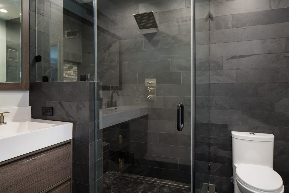 This is an example of a mid-sized transitional master bathroom in Los Angeles with flat-panel cabinets, dark wood cabinets, a corner shower, a one-piece toilet, black tile, slate, grey walls, slate floors, an integrated sink, solid surface benchtops, black floor, a hinged shower door, white benchtops, a shower seat, a double vanity and a floating vanity.