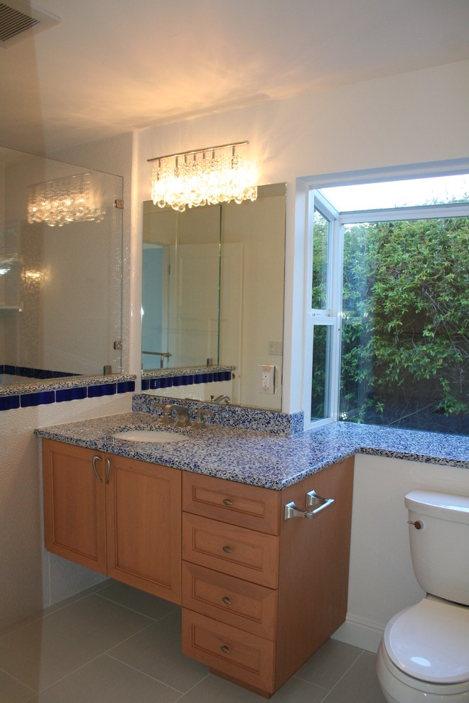 Photo of a transitional bathroom in San Francisco with an undermount sink, recessed-panel cabinets, medium wood cabinets, recycled glass benchtops, a drop-in tub, an open shower, a two-piece toilet, blue tile and glass tile.