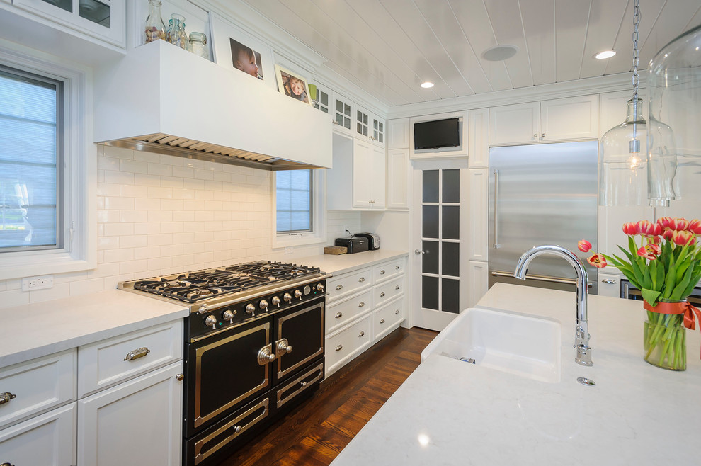 This is an example of a large country u-shaped eat-in kitchen in San Francisco with a farmhouse sink, shaker cabinets, white cabinets, quartzite benchtops, white splashback, ceramic splashback, stainless steel appliances and medium hardwood floors.