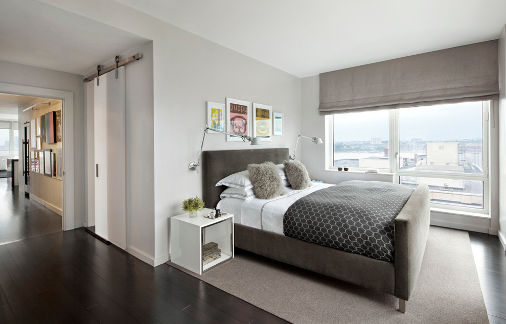 Contemporary bedroom in New York with grey walls and dark hardwood floors.