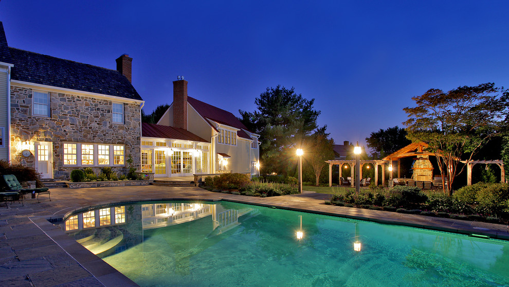 Inspiration for a large traditional pool in DC Metro with natural stone pavers.