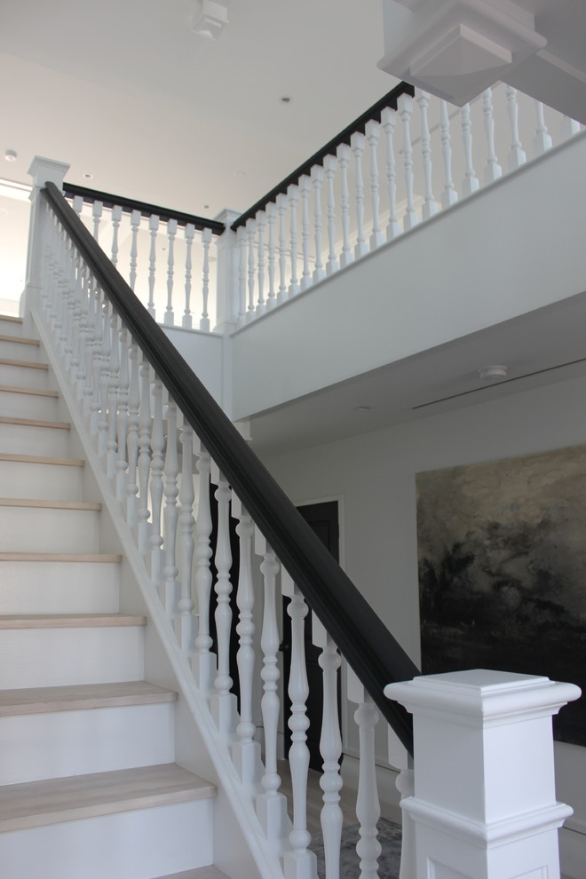Photo of an expansive transitional wood u-shaped staircase in DC Metro with wood risers and wood railing.