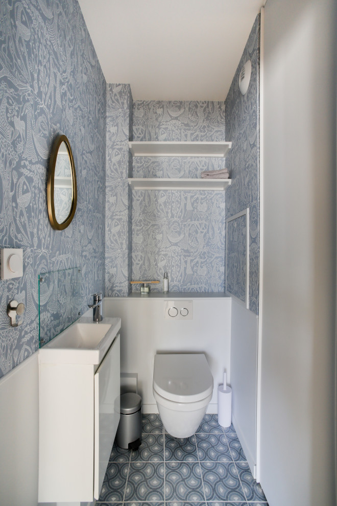 Пример оригинального дизайна: туалет среднего размера в современном стиле с фасадами с декоративным кантом, белыми фасадами, инсталляцией, полом из керамической плитки, подвесной раковиной, синим полом, подвесной тумбой и обоями на стенах