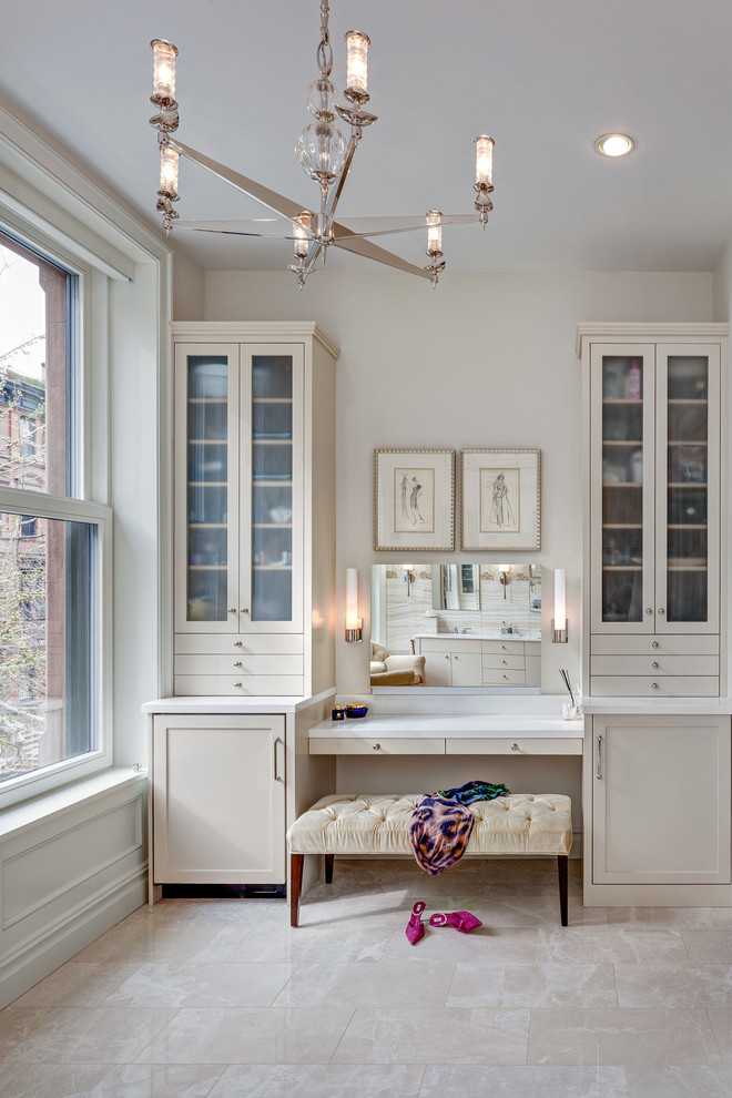 Photo of an expansive transitional women's dressing room in New York with shaker cabinets, beige cabinets and marble floors.