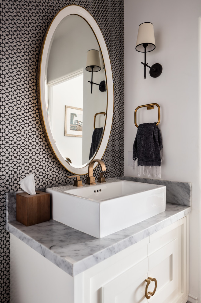 Photo of a beach style powder room in Los Angeles with furniture-like cabinets, white cabinets, multi-coloured walls, a vessel sink and grey benchtops.