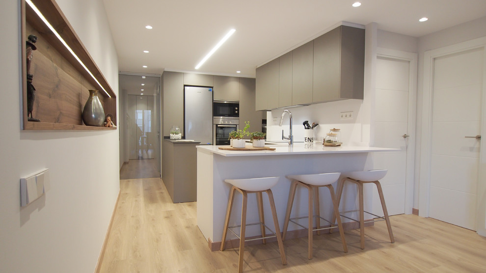 Inspiration for a mid-sized contemporary open plan kitchen in Barcelona with an undermount sink, flat-panel cabinets, grey cabinets, quartzite benchtops, white splashback, stainless steel appliances, medium hardwood floors, a peninsula and brown floor.