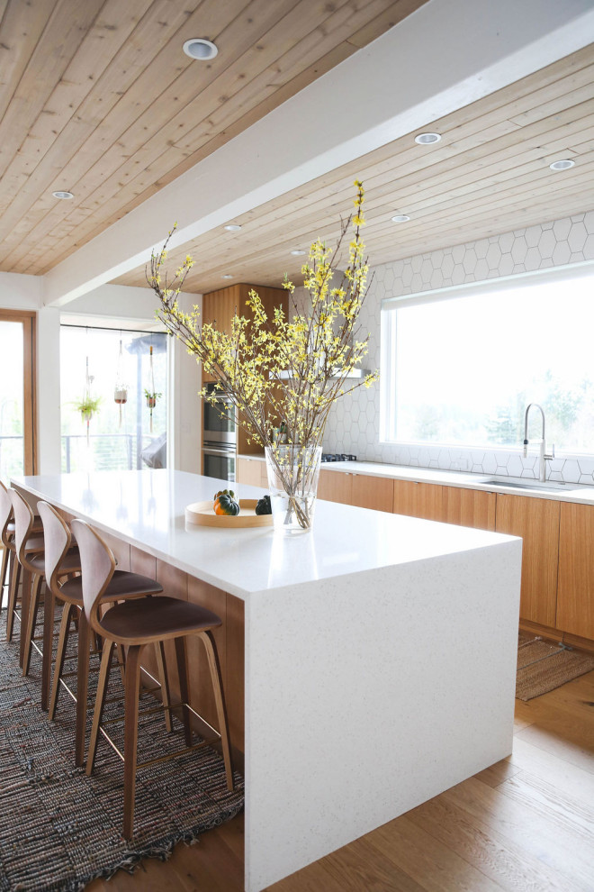 Bild på ett minimalistiskt vit linjärt vitt kök, med en undermonterad diskho, släta luckor, skåp i mellenmörkt trä, bänkskiva i kvarts, vitt stänkskydd, stänkskydd i keramik, rostfria vitvaror, mellanmörkt trägolv, en köksö och brunt golv