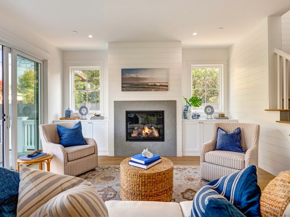 Design ideas for a beach style living room in Los Angeles with white walls, medium hardwood floors, a standard fireplace, brown floor and planked wall panelling.