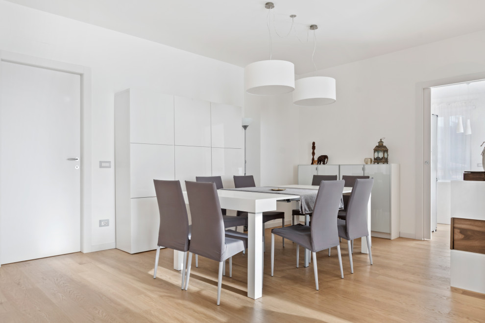 Modern dining room in Milan with white walls and light hardwood floors.