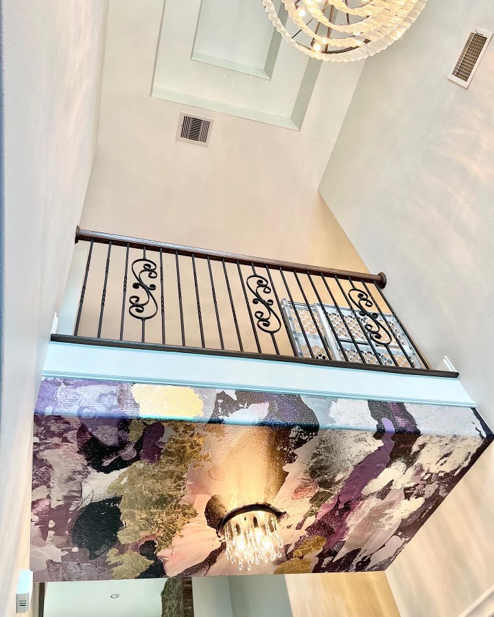 Idée de décoration pour un grand escalier courbe avec un garde-corps en métal et du papier peint.