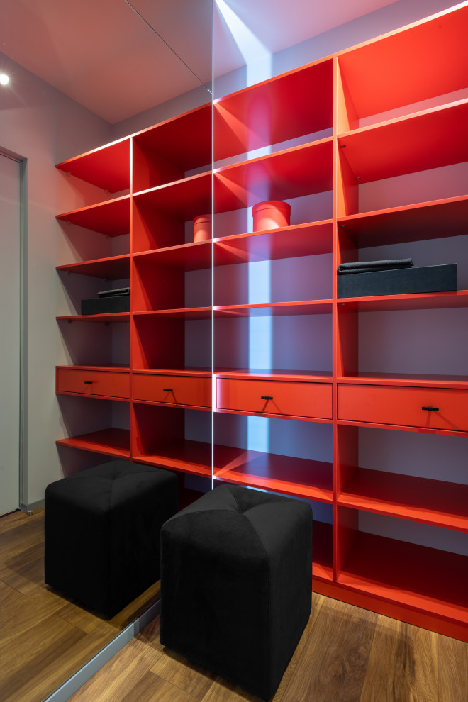 Small contemporary gender-neutral walk-in wardrobe in Yekaterinburg with open cabinets, red cabinets, laminate floors and brown floor.