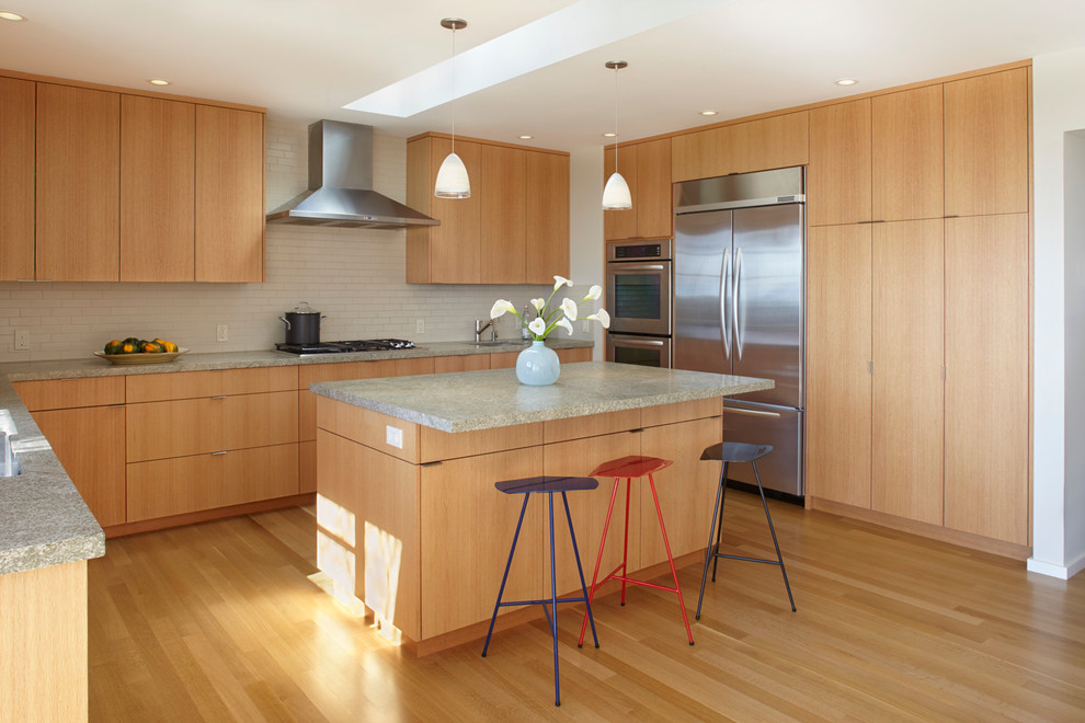 Inspiration for a contemporary l-shaped kitchen in San Francisco with an undermount sink, flat-panel cabinets, light wood cabinets, white splashback, subway tile splashback, stainless steel appliances, light hardwood floors, with island and granite benchtops.