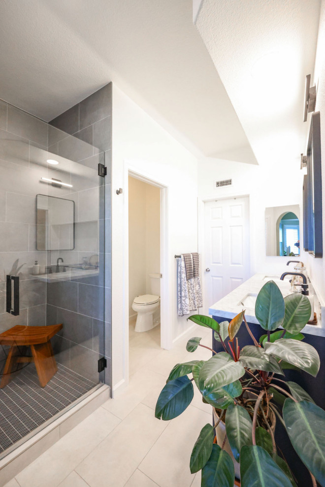 Idéer för att renovera ett mellanstort maritimt flerfärgad flerfärgat en-suite badrum, med skåp i shakerstil, blå skåp, en dusch i en alkov, en toalettstol med separat cisternkåpa, grå kakel, porslinskakel, vita väggar, klinkergolv i porslin, ett undermonterad handfat, marmorbänkskiva, grått golv och dusch med gångjärnsdörr