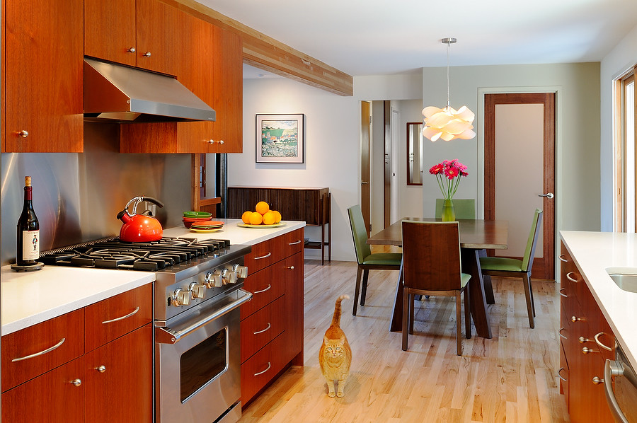 This is an example of a mid-sized contemporary galley eat-in kitchen in Seattle with an undermount sink, flat-panel cabinets, medium wood cabinets, quartzite benchtops, metallic splashback, metal splashback, stainless steel appliances, light hardwood floors and no island.