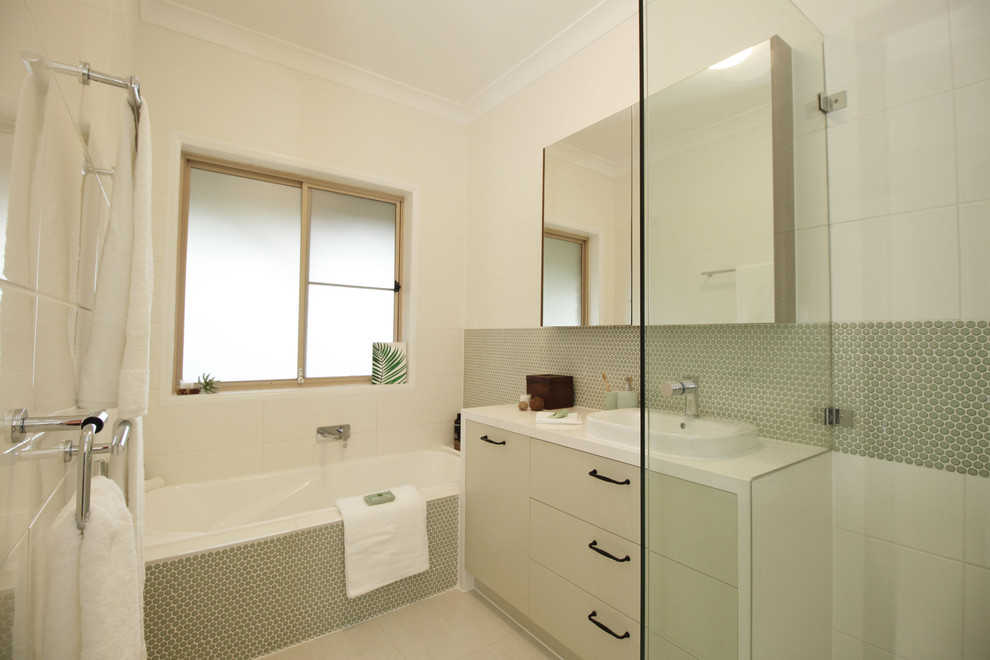 Design ideas for a small contemporary kids bathroom in Brisbane with flat-panel cabinets, green cabinets, a drop-in tub, a curbless shower, a two-piece toilet, white tile, mosaic tile, white walls, porcelain floors, a vessel sink, engineered quartz benchtops, beige floor, a hinged shower door and white benchtops.