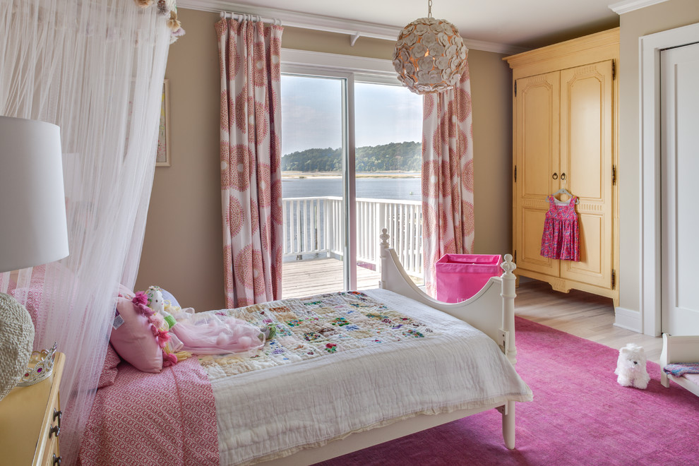 This is an example of a kids' bedroom for girls in New York with beige walls and light hardwood floors.