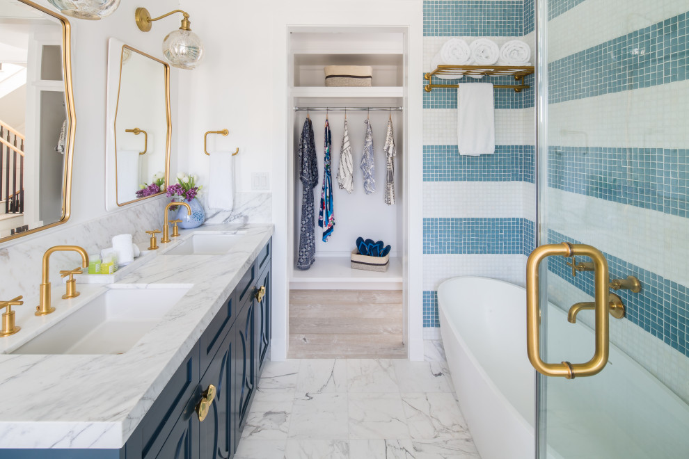 Immagine di una stanza da bagno costiera con ante blu, vasca freestanding, doccia ad angolo, piastrelle multicolore, piastrelle di vetro, top in marmo, top bianco e due lavabi