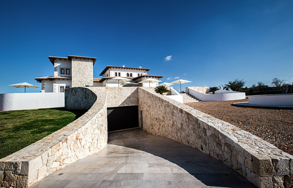This is an example of a large country three-storey exterior in Palma de Mallorca with stone veneer.