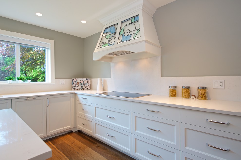 Eat-in kitchen - mid-sized transitional u-shaped medium tone wood floor and brown floor eat-in kitchen idea in Vancouver with an undermount sink, beaded inset cabinets, white cabinets, quartzite countertops, white backsplash, stone slab backsplash, paneled appliances and an island