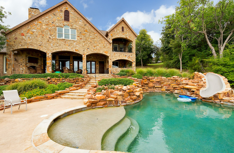 Photo of a mid-sized mediterranean backyard custom-shaped natural pool in Dallas with a water slide and natural stone pavers.