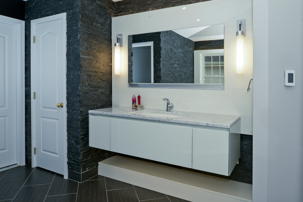 Large contemporary master bathroom in Other with flat-panel cabinets, white cabinets, a freestanding tub, gray tile, stone tile, grey walls, porcelain floors, an undermount sink, marble benchtops and grey floor.