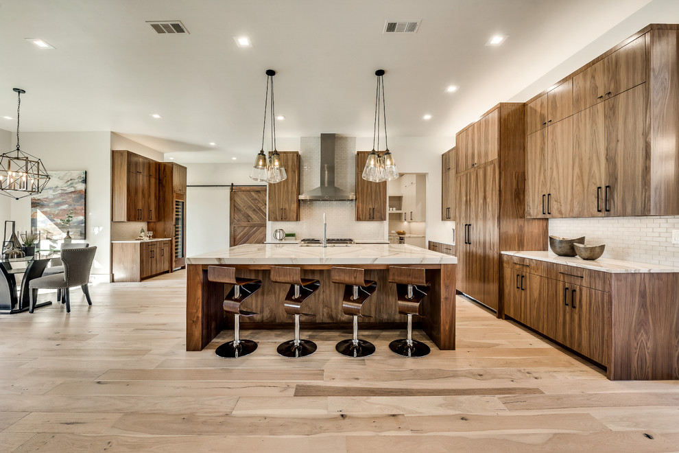 Photo of a large contemporary u-shaped eat-in kitchen in Dallas with flat-panel cabinets, medium wood cabinets, quartz benchtops, white splashback, ceramic splashback, panelled appliances, with island, an undermount sink, light hardwood floors, beige floor and white benchtop.