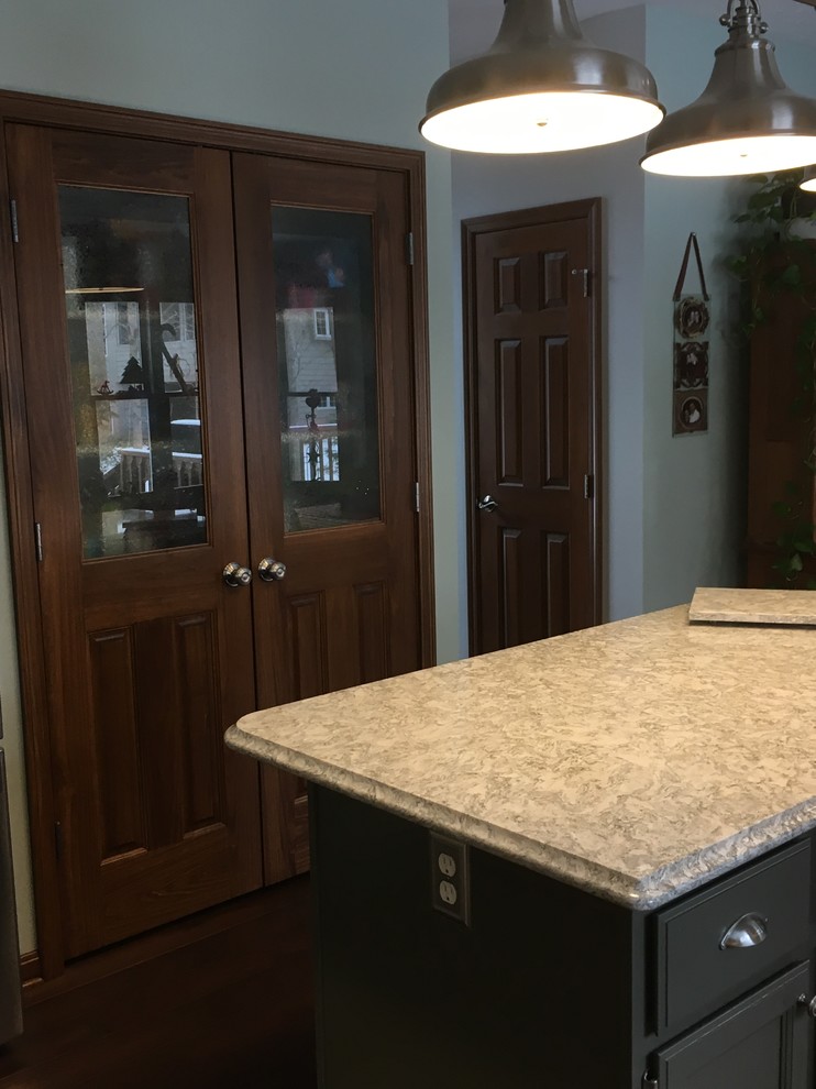 Example of a mid-sized transitional u-shaped medium tone wood floor enclosed kitchen design with an undermount sink, white cabinets, quartz countertops, white backsplash, subway tile backsplash, stainless steel appliances and an island