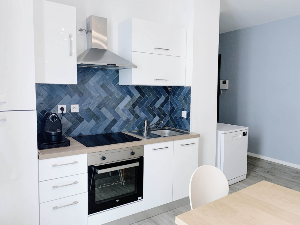 Design ideas for a small contemporary single-wall open plan kitchen in Marseille with an undermount sink, white cabinets, wood benchtops, blue splashback, terra-cotta splashback, stainless steel appliances, light hardwood floors, beige floor and beige benchtop.