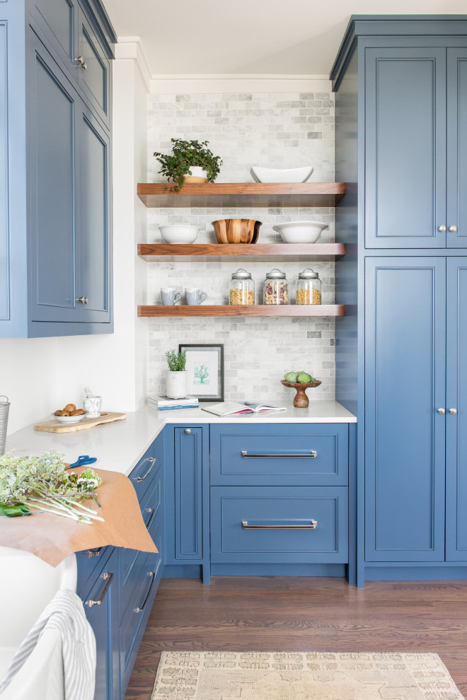 Example of a beach style medium tone wood floor kitchen pantry design in Charleston with a farmhouse sink, blue cabinets, marble countertops, gray backsplash and no island