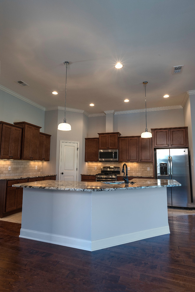 Open concept kitchen - mid-sized transitional l-shaped medium tone wood floor open concept kitchen idea with an undermount sink, shaker cabinets, medium tone wood cabinets, granite countertops, beige backsplash, stone tile backsplash, stainless steel appliances and an island