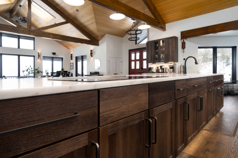 Example of a huge mountain style single-wall dark wood floor, brown floor and shiplap ceiling open concept kitchen design in Denver with a farmhouse sink, shaker cabinets, dark wood cabinets, marble countertops, paneled appliances, an island and white countertops