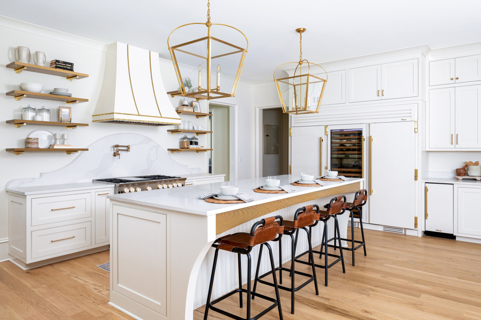Transitional kitchen in Charlotte with a farmhouse sink, beaded inset cabinets, white cabinets, quartz benchtops, white splashback, engineered quartz splashback, coloured appliances, light hardwood floors, with island, brown floor and white benchtop.